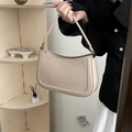 Beige faux leather shoulder bag with gold hardware held in a warm lifestyle setting - Khaki