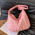 Stylish pink quilted puffer tote bag with wide shoulder strap on a black leather sofa - Pink