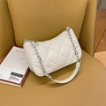 Quilted white shoulder bag with silver chain strap on a vintage leather sofa - Beige