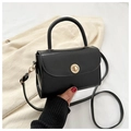 Detail of black mini crossbody bag featuring a gold sunburst twist lock and leather texture - Black