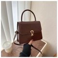 Detail of a brown leather crossbody bag featuring a gold horseshoe metal clasp and handle - Brown
