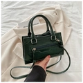 Detail of dark green textured handbag showing zip accents and silver-tone hardware - Green