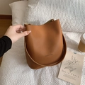 Sac seau marron en cuir grainé avec large bandoulière dans une ambiance décontractée - Marron