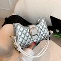 Silver quilted metallic handbag with gold buckle and white strap on a cozy sofa - Silver