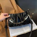 Black pleated cloud bag with elegant pearl and gold flower chain on a vintage book - Black
