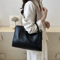 Minimalist black faux leather tote bag for office wear shown on a model's shoulder - Black