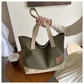 Bolso tote de lona verde oliva y beige con parche de cuero sobre mesa de madera - Verde