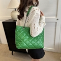 Quilted bright green tote bag with chain strap shown on model in a modern interior - Green