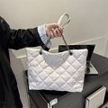 White quilted tote bag with silver chain straps shown in a stylish handheld indoor setting - White