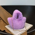 Mini sac seau violet en fausse fourrure avec chaîne dorée sur une chaise noire - Violet