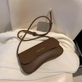 Dark brown crescent crossbody bag with unique curved design and knot detail shoulder strap - Brown
