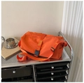 Close-up of orange waterproof sports bag with adjustable strap on a silver metal trolley - Orange Large