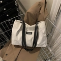 Weiße Cord-Tragetasche mit schwarzen Lederriemen und Mode-Label im Einkaufswagen - Weiß