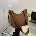 Bolso hobo minimalista de cuero marrón con correa ancha sobre un escritorio moderno - Marrón Oscuro