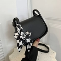 Mini black leather saddle bag with stylish checkered ribbon handle detail and shoulder strap - Black
