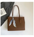 Detail of brown litchi pattern leather tote bag with a decorative silk scarf on strap - Brown
