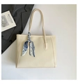 Macro view of creamy white pebbled leather tote bag with stylish patterned silk scarf - White