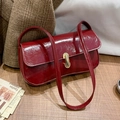 Retro burgundy patent leather baguette bag with gold buckle on a rustic wooden surface - Red