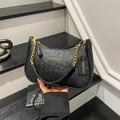 Schicke schwarze Halbmond-Tasche mit Straußenleder-Textur und goldener Kette im Lifestyle - Schwarz