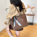 Bolso tote de cuero marrón con pañuelo floral llevado al hombro por una modelo - Marrón