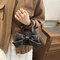 Sac seau noir avec grand nœud et rivets en étoile porté par un mannequin en intérieur - Café
