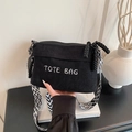 Black corduroy tote bag featuring white embroidery and a geometric wide shoulder strap - Black