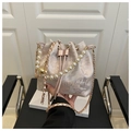 Detalle de bolso tipo saco de seda rosa con asa de perlas y correa de cadena metálica - Rosa
