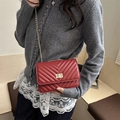 Red chevron quilted crossbody bag with gold chain strap worn over a grey knit sweater - Red