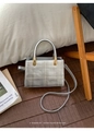 Close-up of a silver quilted leather crossbody bag with metallic handles and gold hardware - Silver