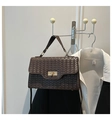 Detail of dark brown woven leather texture and gold twist-lock on stylish handbag - Coffee