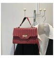 Macro detail of wine red woven leather texture and elegant golden metal twist lock - Red