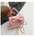 Dettaglio borsa rosa da bambina con manico di perle, fiocco e tracolla dorata - Rosa