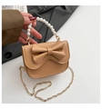 Dettaglio della borsa da bambina beige con fiocco grande, manico di perle e catena d'oro - Marrone