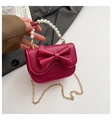 Dettaglio della borsa a tracolla rosso rosa con fiocco in pelle e manico in perle bianche - Rosso