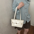 Chic cream white leather shoulder bag featuring decorative belt buckles and metal eyelets - White
