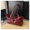 Detail of burgundy glossy patent leather tote bag with buckles in an office setting - Red