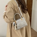 Nahaufnahme der silbernen Stepptasche mit Holzperlen-Anhänger am beigen Trenchcoat - Silber Mit Anhänger