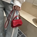 Glänzende rote Mini-Handtasche mit gewellter Klappe und Trageriemen am Modell - Rot
