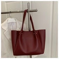 Detail view of a large burgundy tote bag in matte leather hanging on a rack - Red