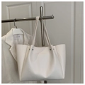 Detail view of large white leather tote bag with silver rivets hanging on metal hanger - White