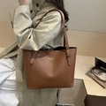 Bolso tote grande de cuero marrón oscuro llevado por una modelo en una gabardina elegante - Marrón