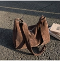 Détail de la texture d'un sac cabas en daim marron foncé avec logo sous le soleil - Brun Cacao