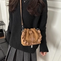 Brown suede bucket bag with woven handle and drawstring closure shown on a model - Brown