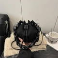 Mini black suede bucket bag with braided handle and drawstring closure on a wooden desk - Black