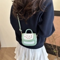 Mint green and white cherry crossbody bag worn by a model in a navy sweatshirt - Green