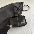 Minimalist black glossy leather crossbody bag with white stitching and gold logo - Black