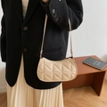 Chic beige quilted underarm bag with slim shoulder strap worn by model in office setting - Off White