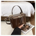 Detail of a deep brown patent leather box bag with gold metal hardware and a top handle - Coffee