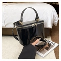 Macro shot of black glossy vanity bag featuring gold hardware and dual zipper closure - Black