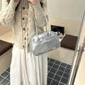 Silver metallic shoulder bag with bow detail on female model in stylish warm setting - Silver